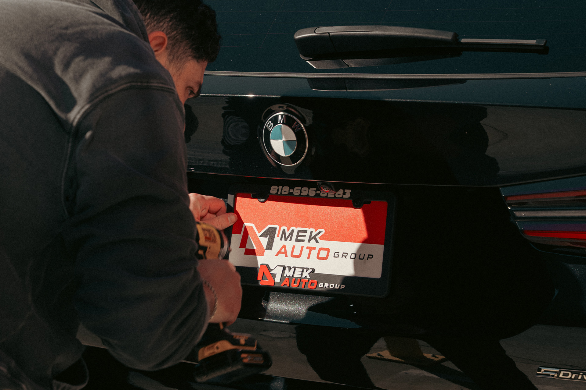 auto broker installing mek auto group license plate frame and cover on black bmw