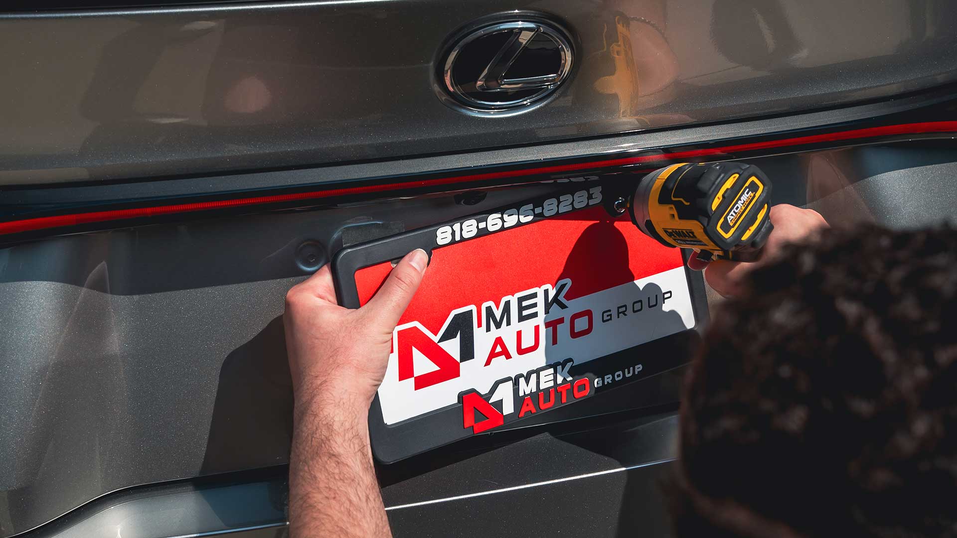 mek auto group auto broker installing license plate frame on new car